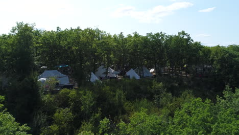 Aerial-view-of-tents-in-a-forest.-Camping-site-in-France,-sunny-day.
